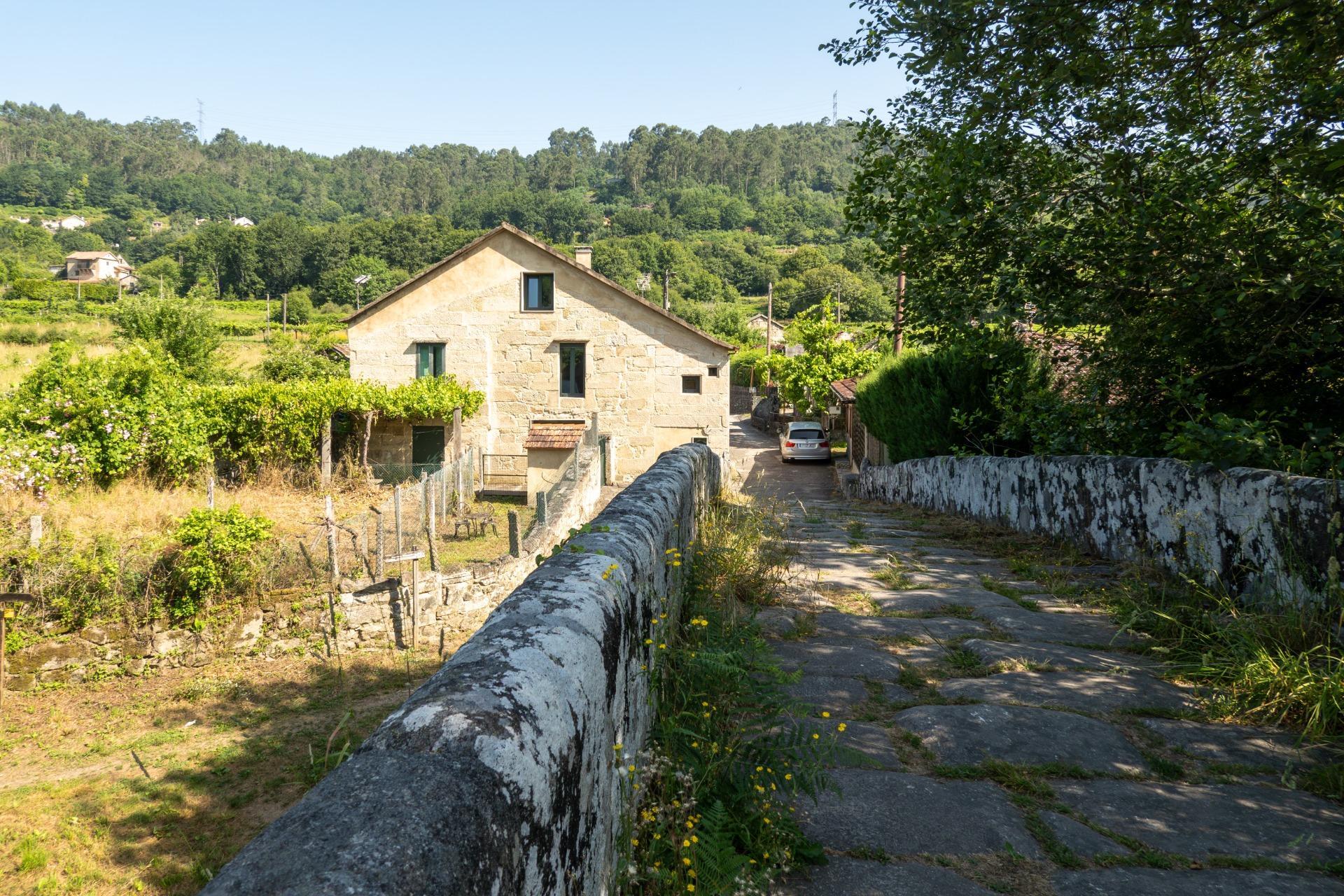 Casa de piedra reformada con jardín frente al puente romano de Cernadela (Mondariz)